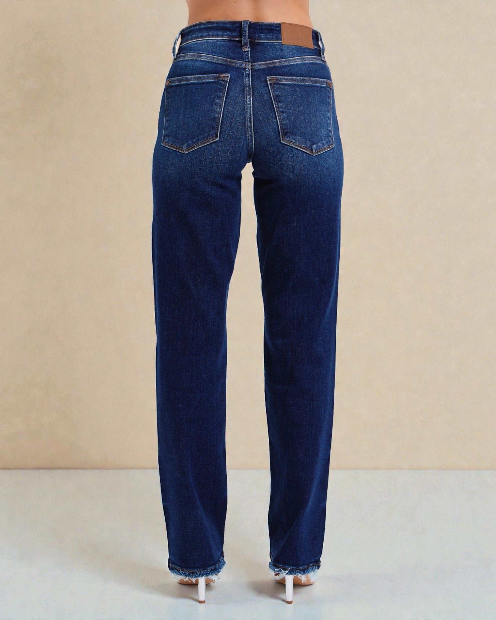 Blue jeans worn by a person on a beige background