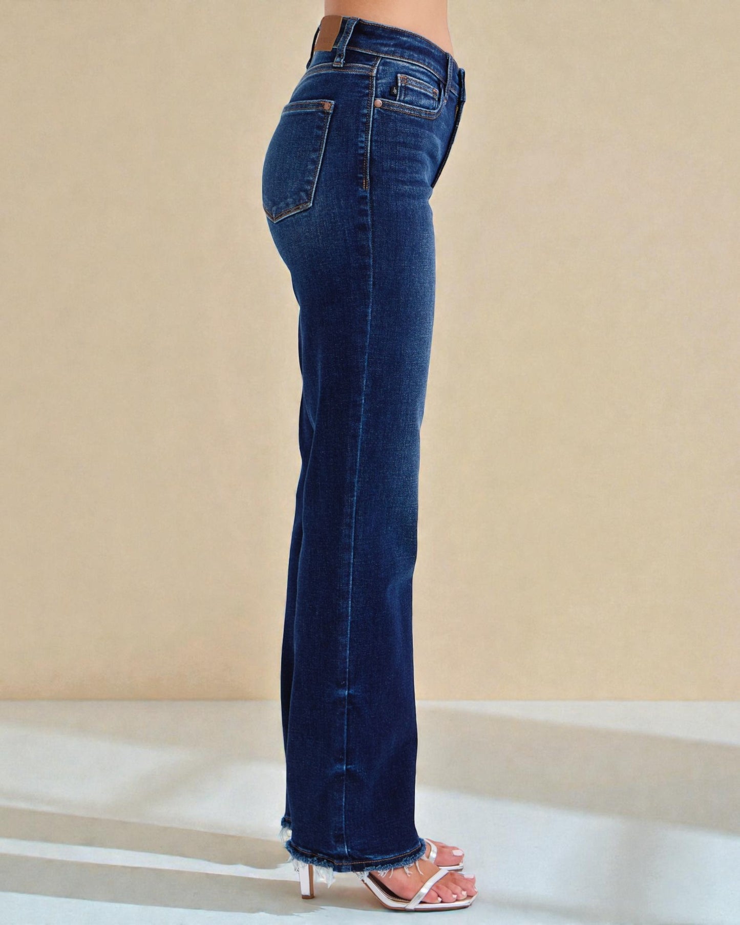 Blue jeans worn by a person on a beige background