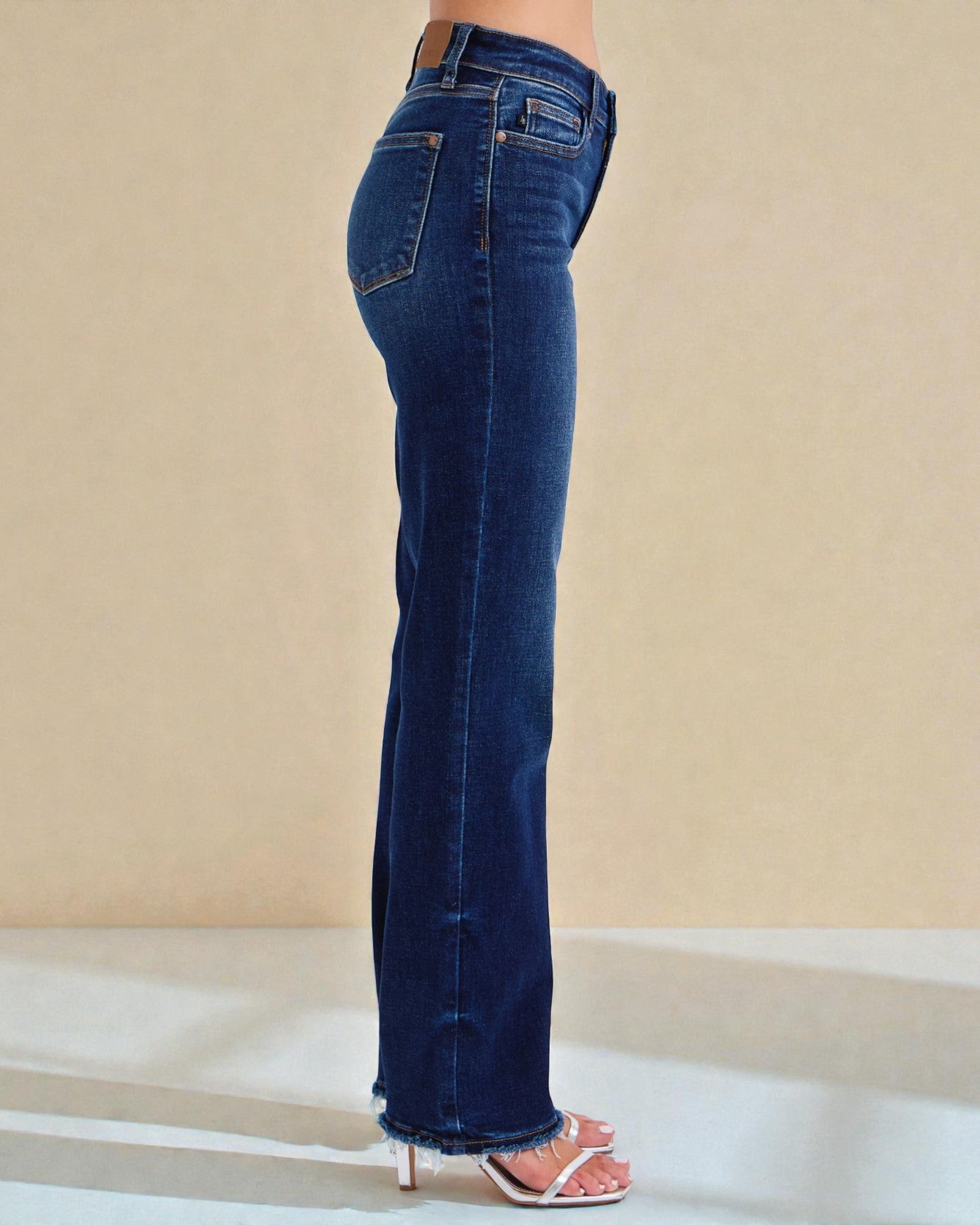 Blue jeans worn by a person on a beige background