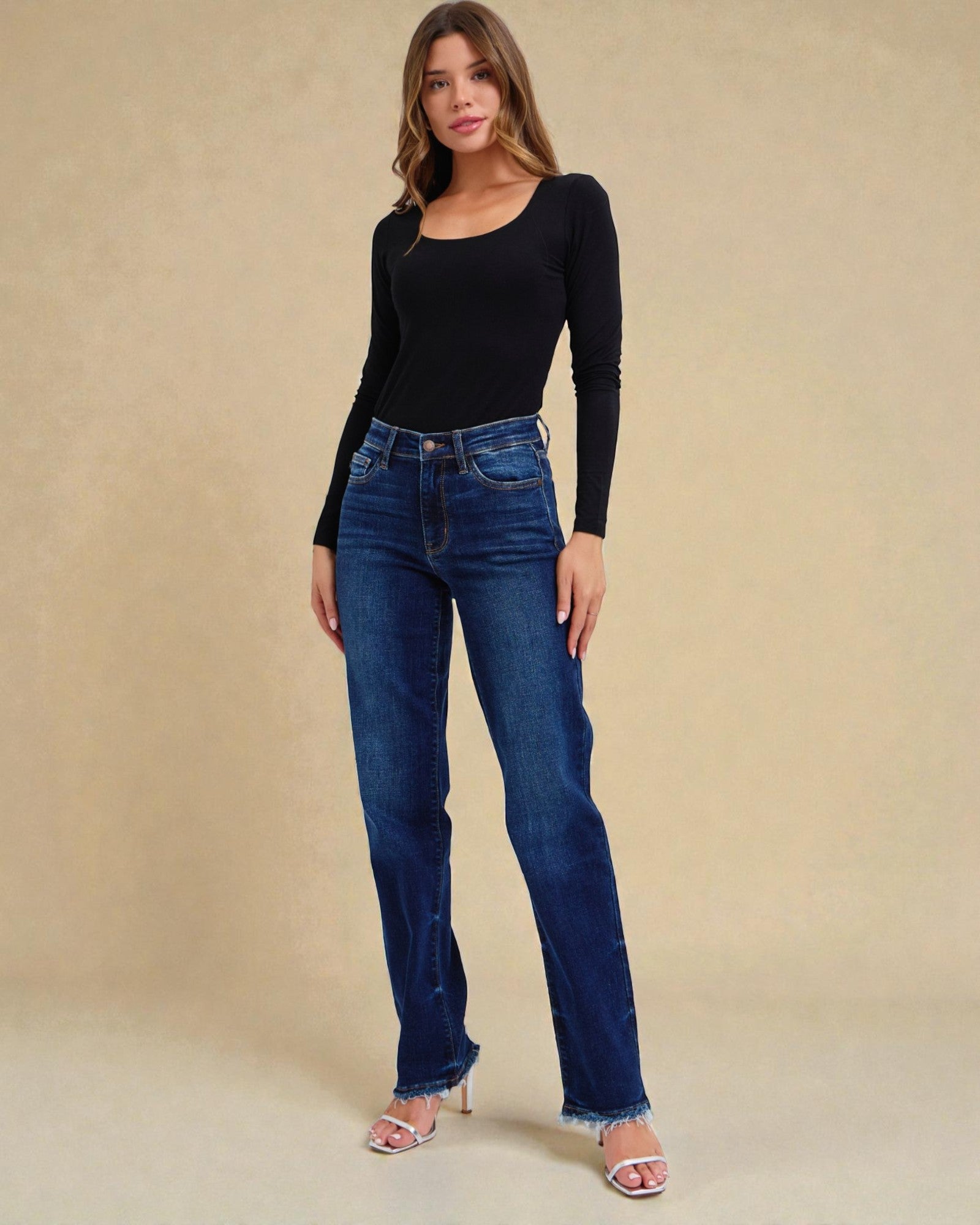 Woman wearing blue jeans and a black top on a beige background