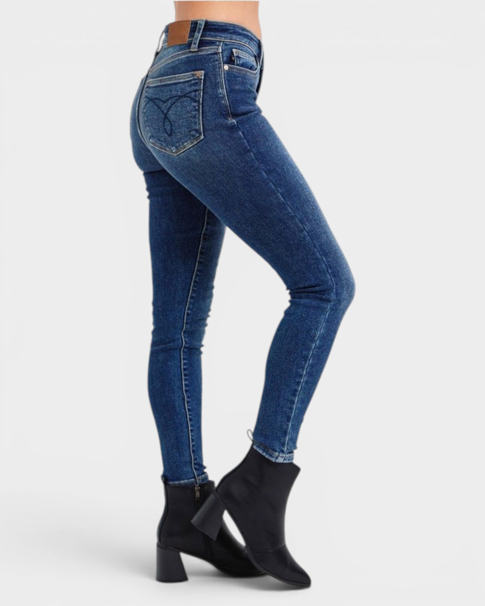 Person wearing blue jeans and black ankle boots on a white background
