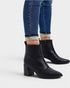 Black ankle boots worn with blue jeans on a white background