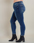 Person wearing blue jeans and black ankle boots on a plain background