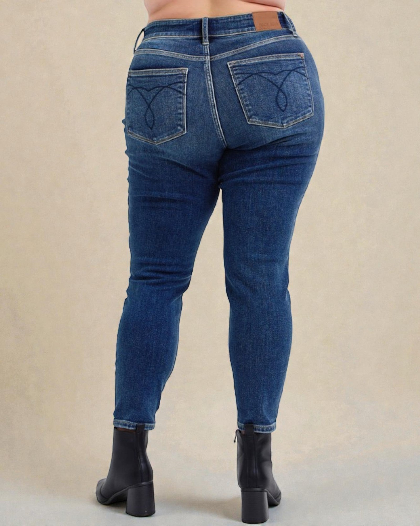 Blue jeans worn by a person on a beige background