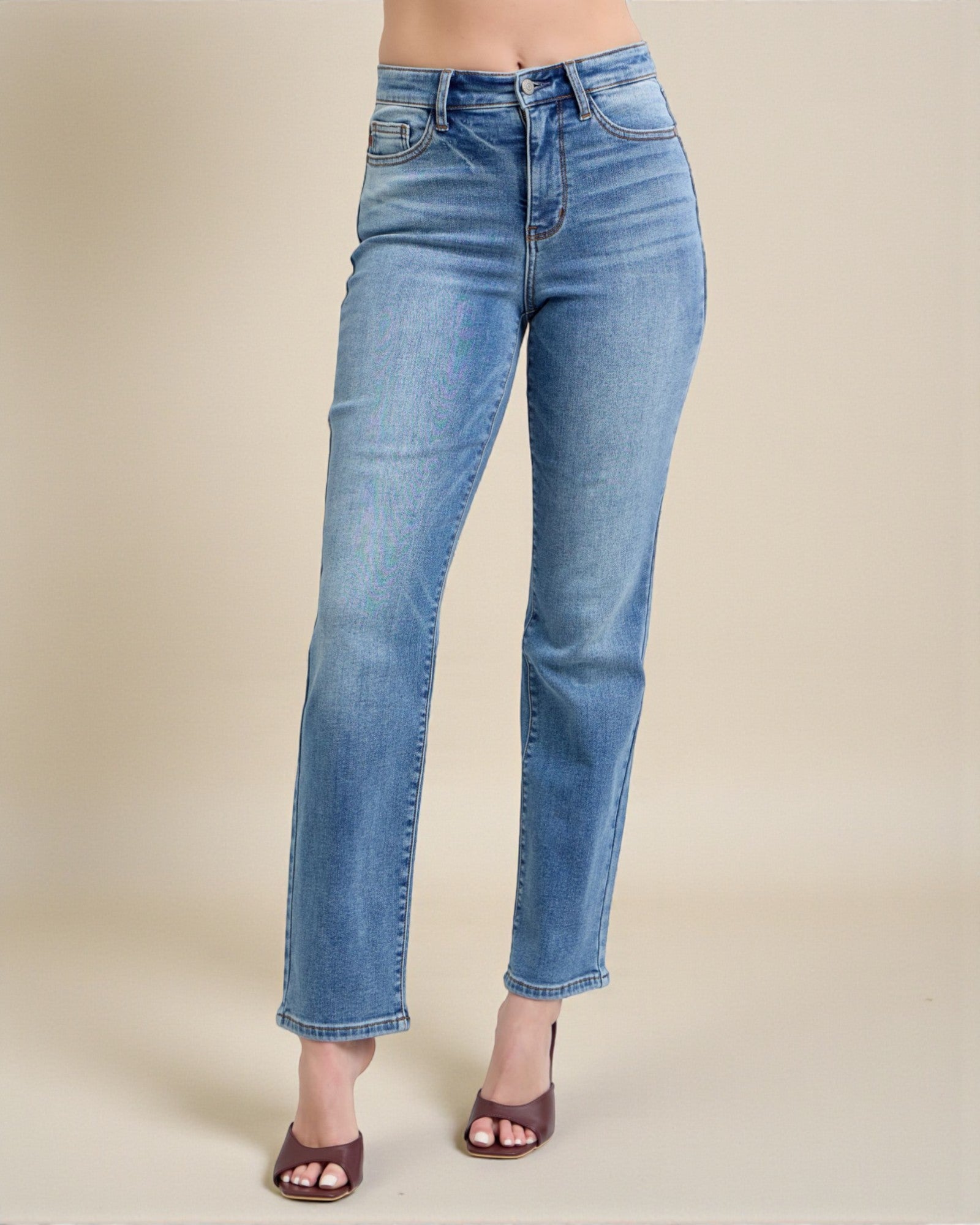 Blue jeans worn by a person on a beige background