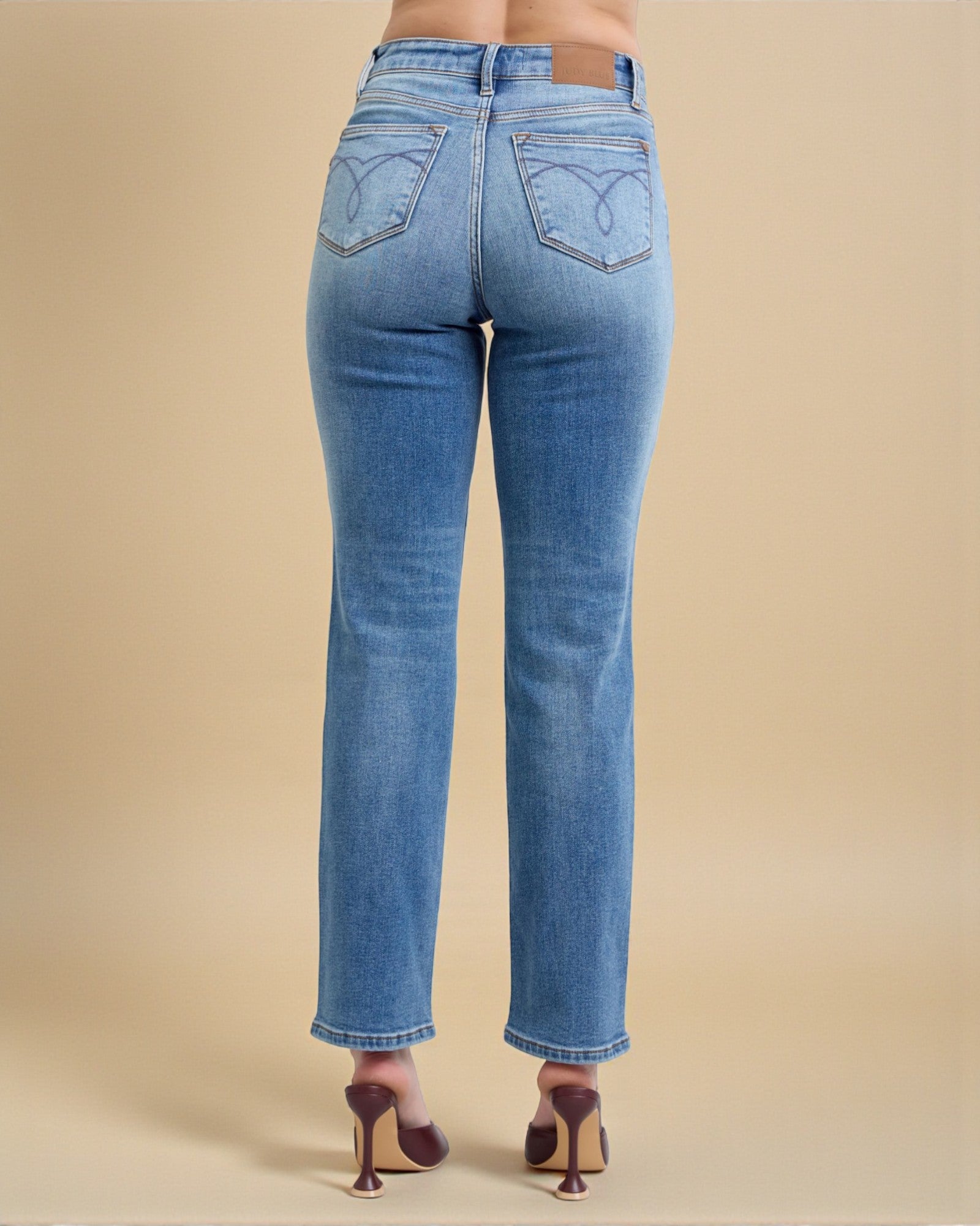 Blue jeans worn by a person on a beige background