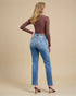 Woman wearing blue jeans and a brown top on a beige background