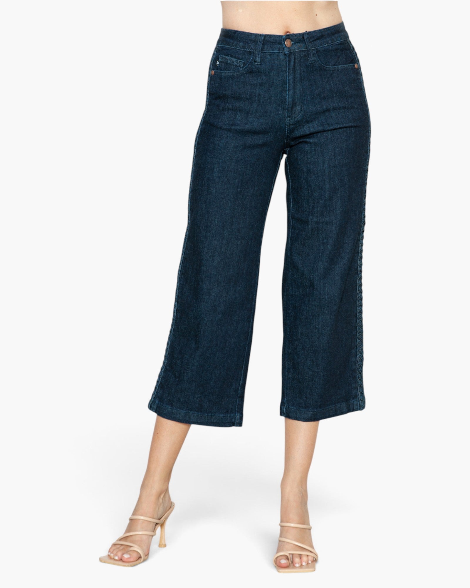 A model wearing dark blue cropped wide-leg denim jeans and beige strappy high-heeled sandals, shown from the waist down against a plain white background.