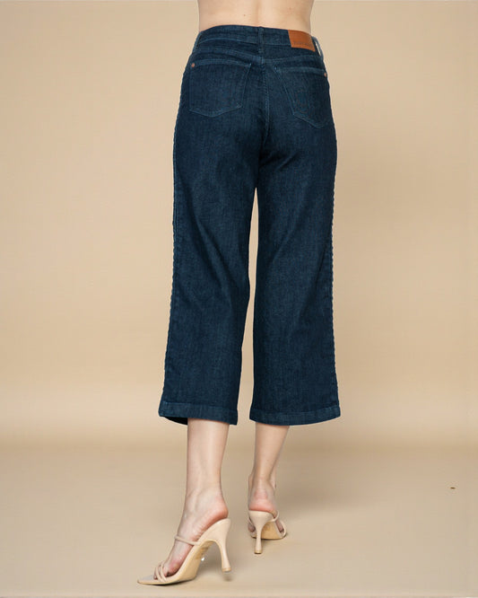 Dark blue jeans worn by a person on a beige background