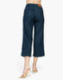 Back view of a model wearing dark blue cropped denim jeans and beige high-heeled sandals against a plain white background.