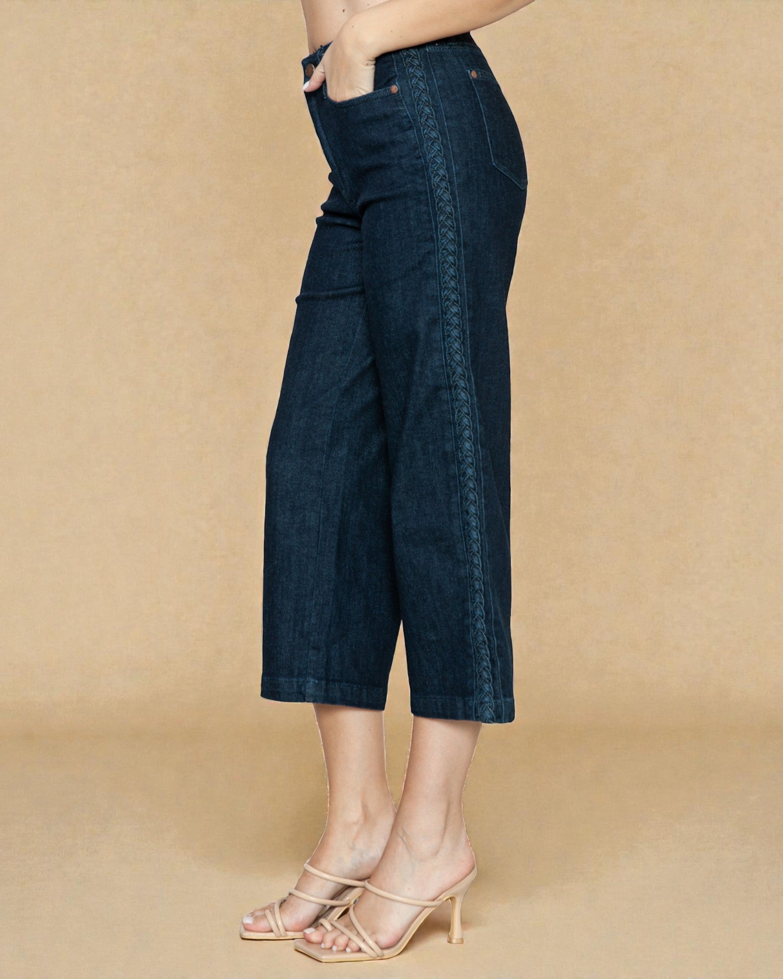 Person wearing dark blue denim culottes on a beige background
