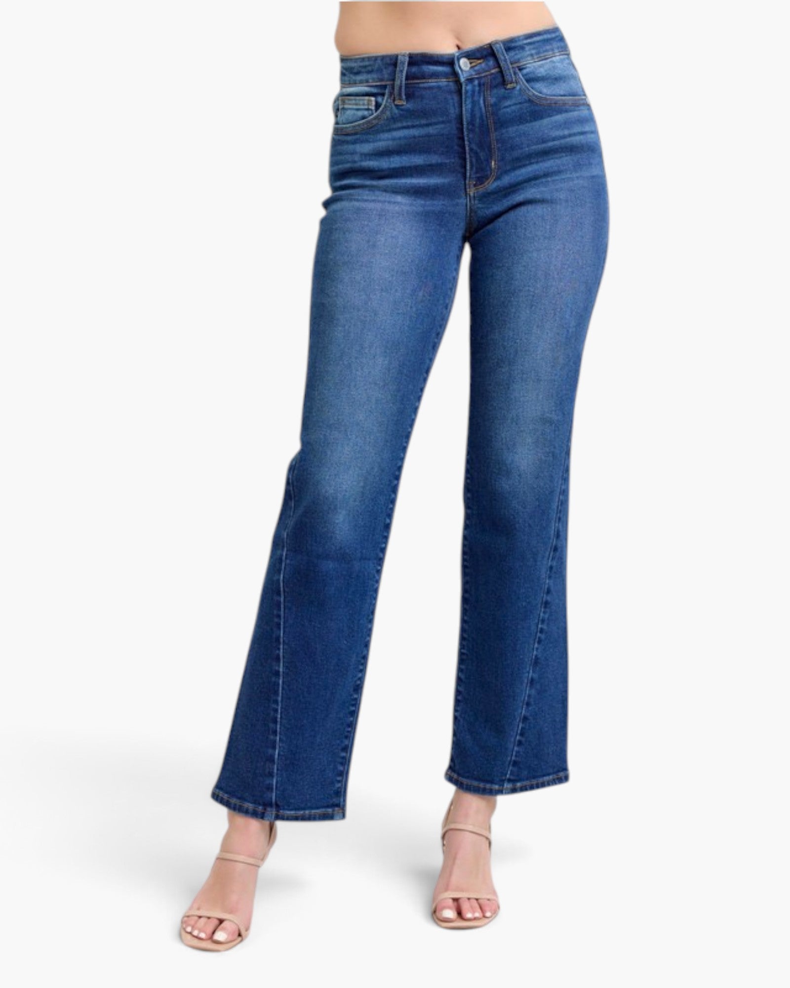 A model wearing a pair of medium-wash blue denim flare jeans with a straight-to-slightly-flared leg, paired with nude heeled sandals against a plain white background.
