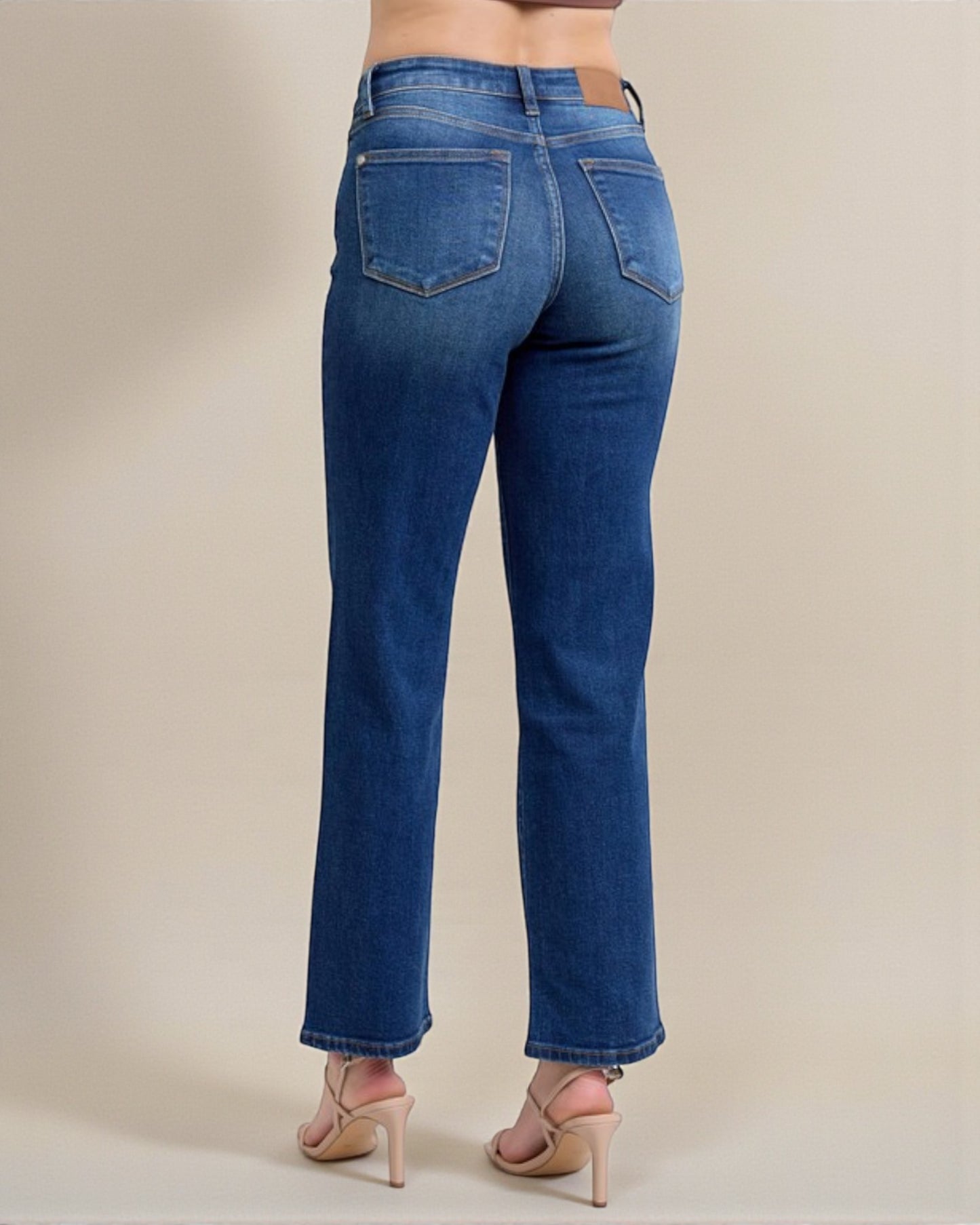 Blue jeans worn by a person on a beige background