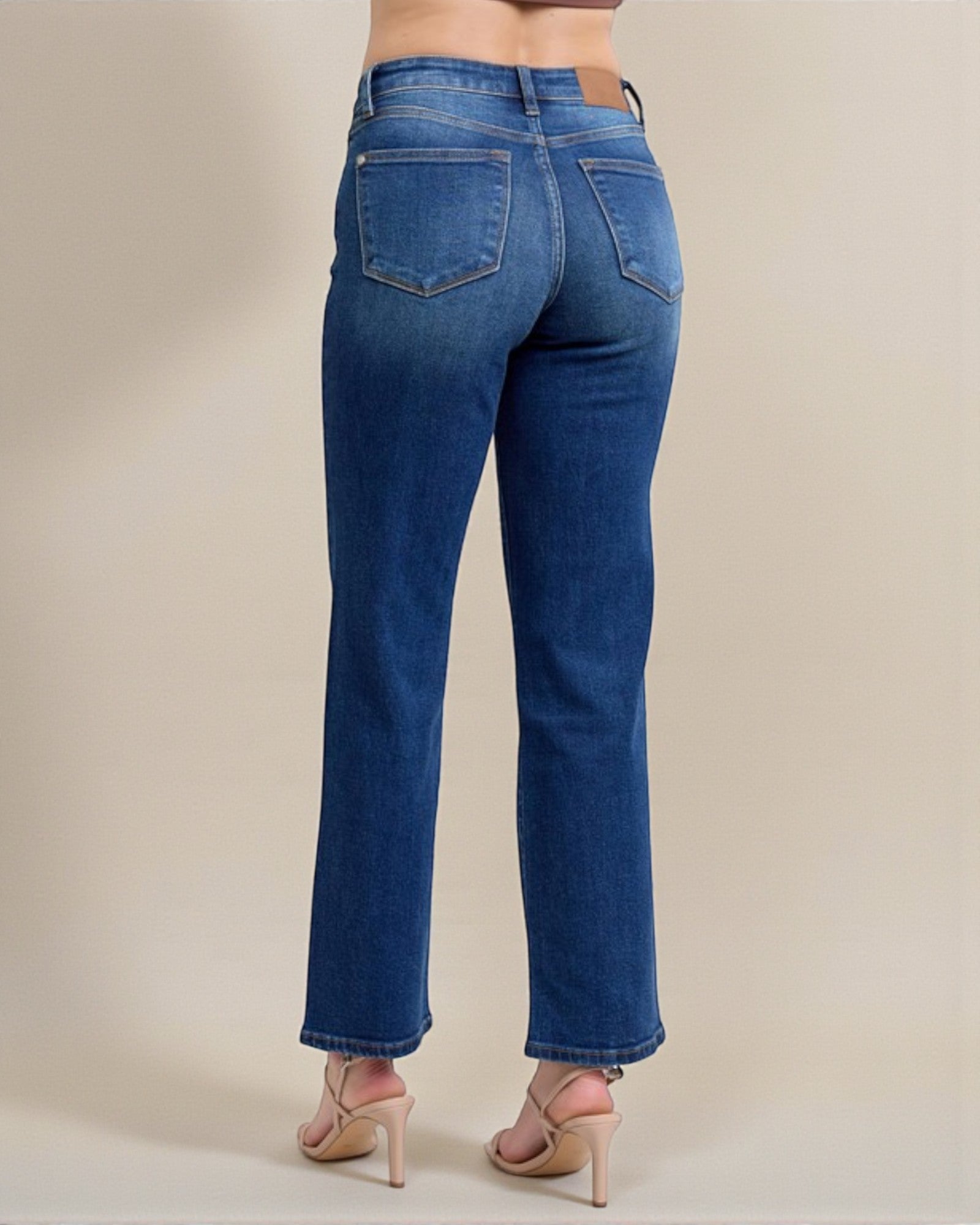 Blue jeans worn by a person on a beige background