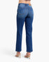 Rear view of a model wearing blue denim jeans and beige high-heeled sandals against a plain white studio background.