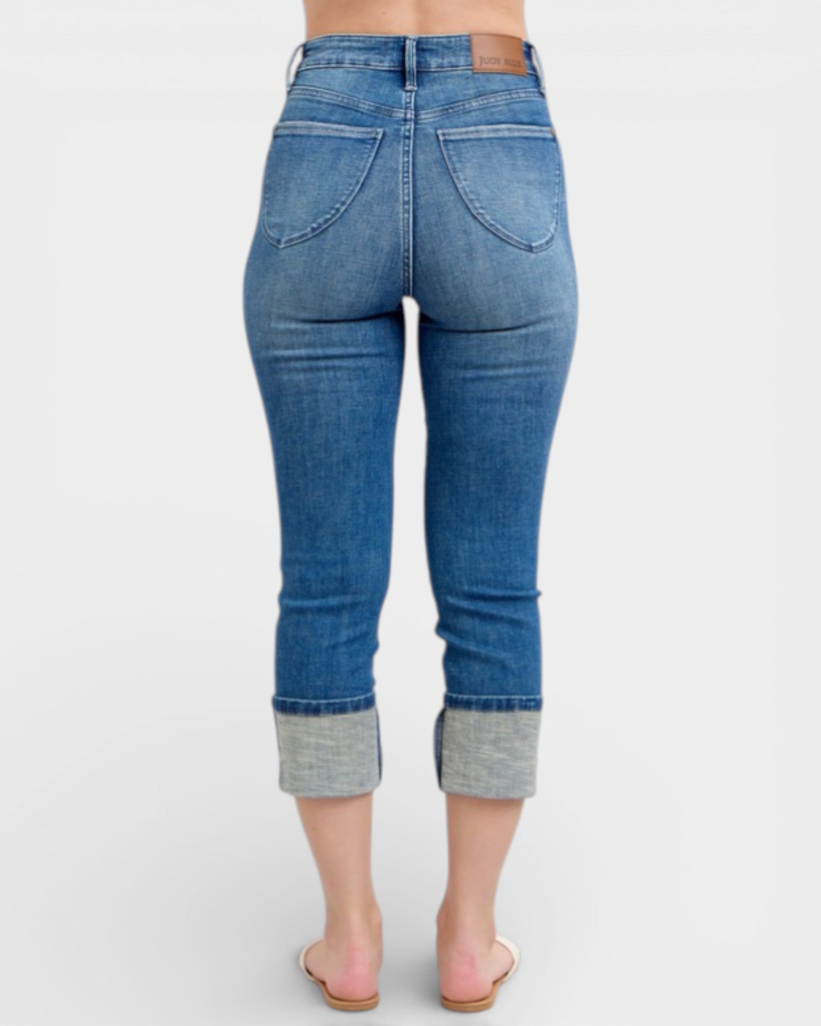 Blue jeans with cuffed ankles on a white background