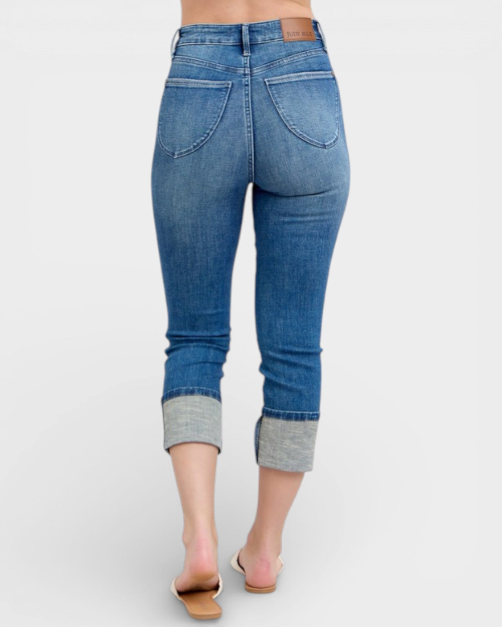 Blue jeans with cuffed ankles on a white background