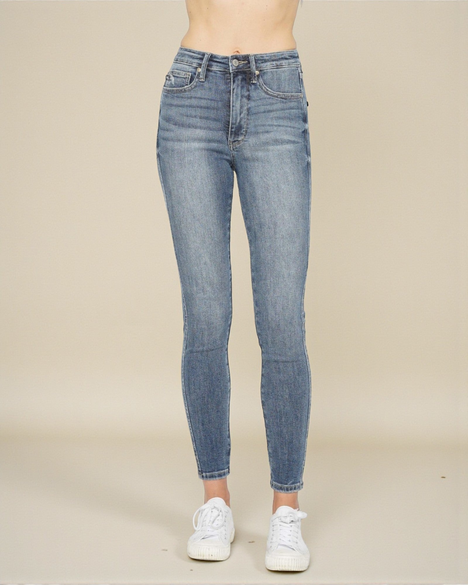Blue jeans worn by a person on a beige background