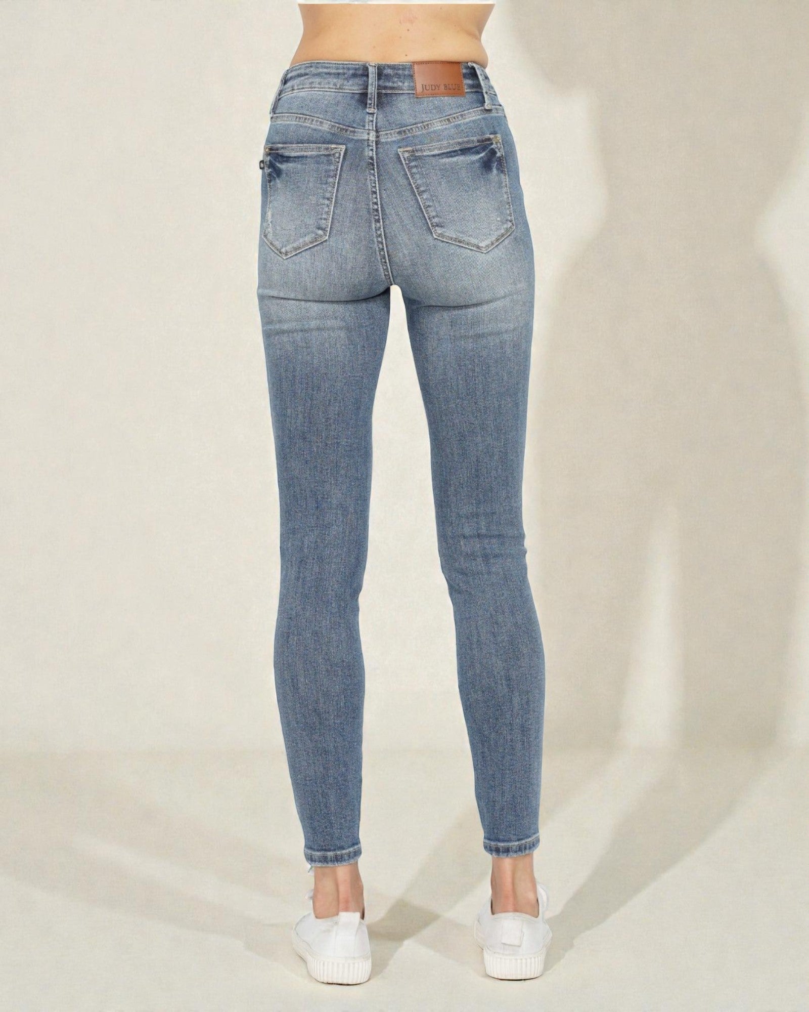 Blue jeans worn by a person on a plain background