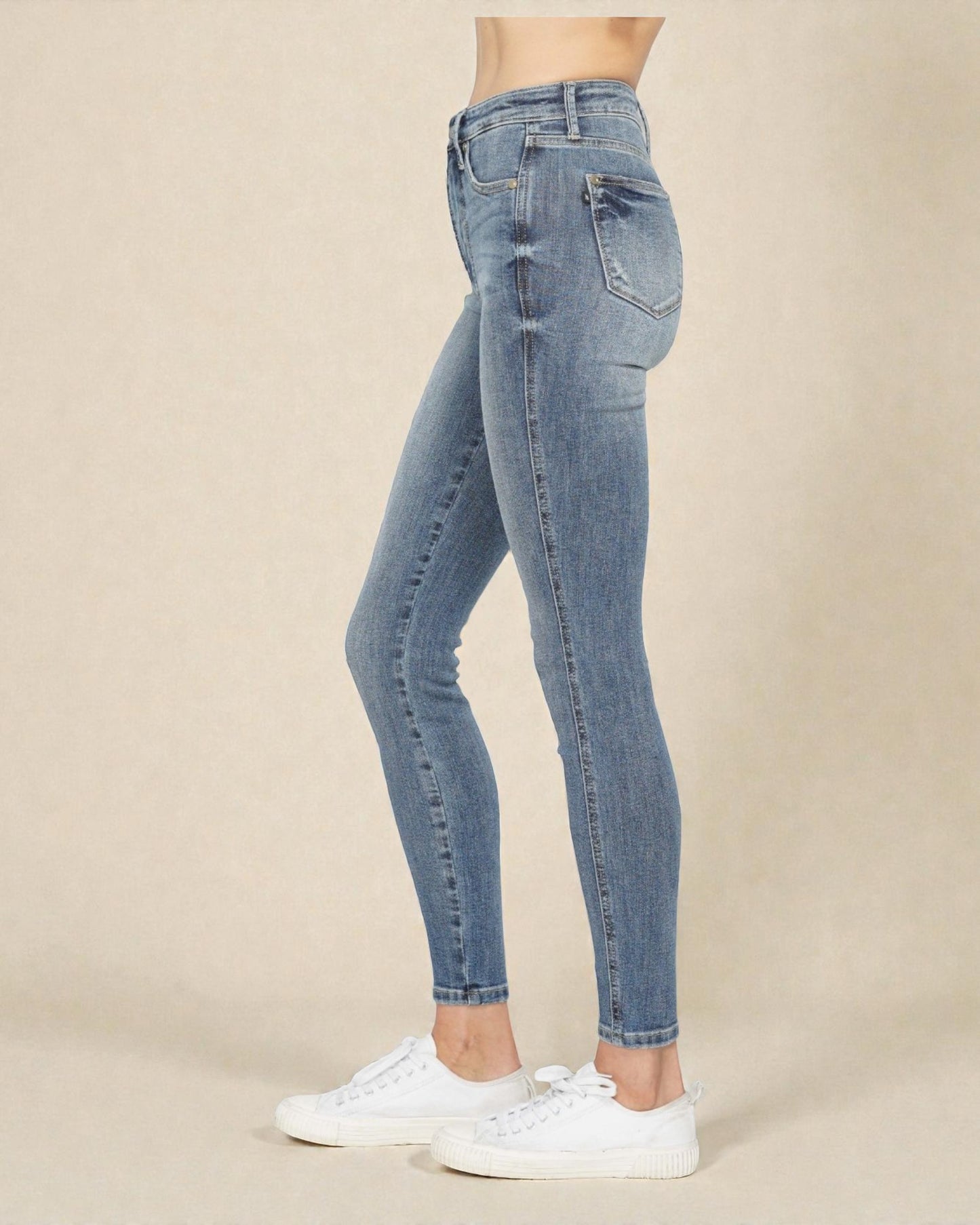 Blue jeans worn by a person on a beige background