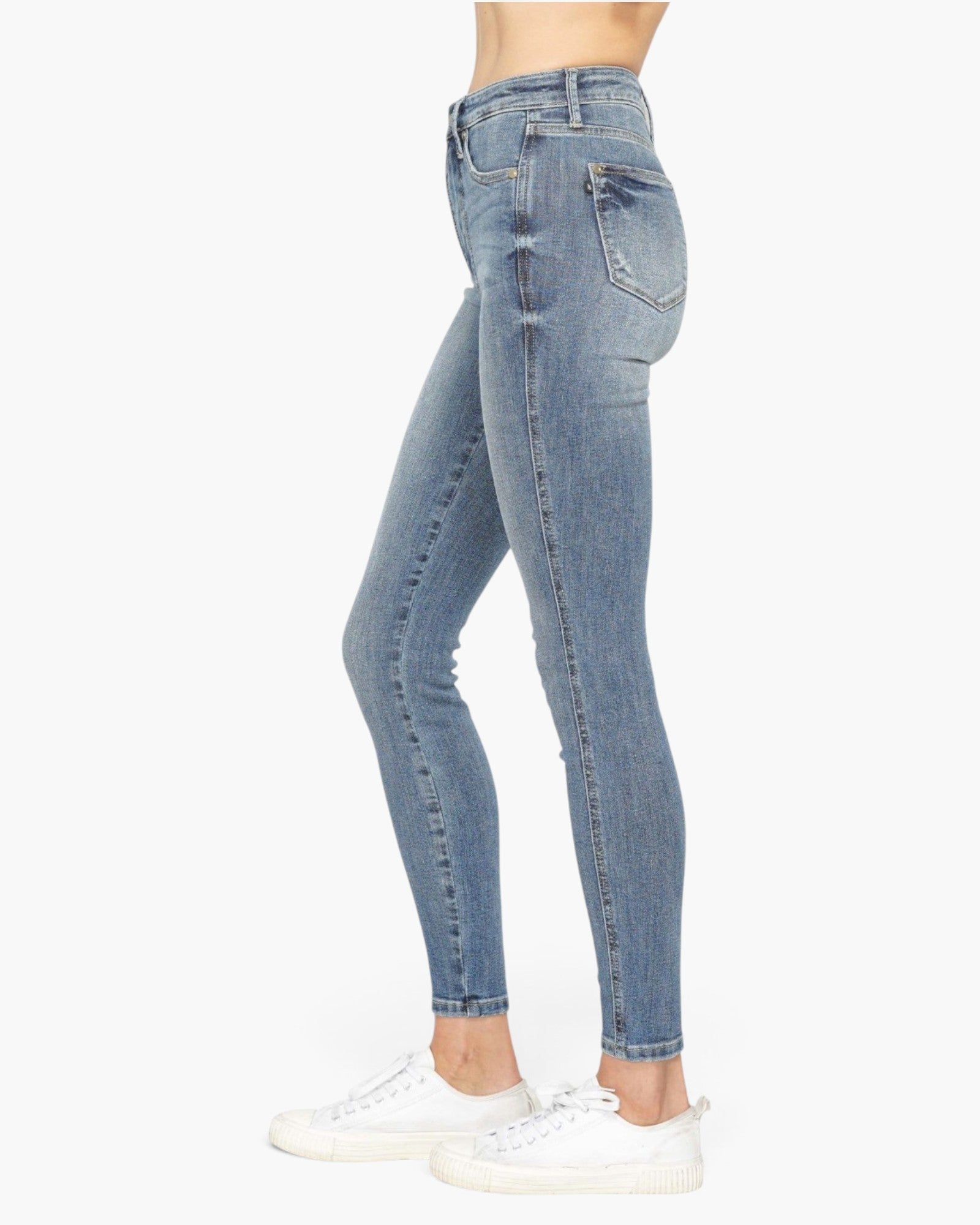 Light blue high-waisted skinny jeans shown on a model from the waist down, paired with white sneakers against a plain white background.