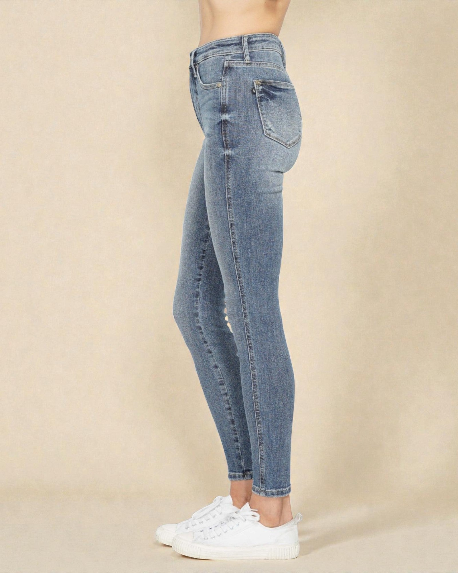 Blue jeans worn by a person on a beige background