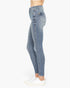 Side view of a person wearing light blue high-waisted skinny jeans with white sneakers, shown against a plain white studio background.