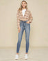 Woman wearing a plaid shirt and jeans on a beige background