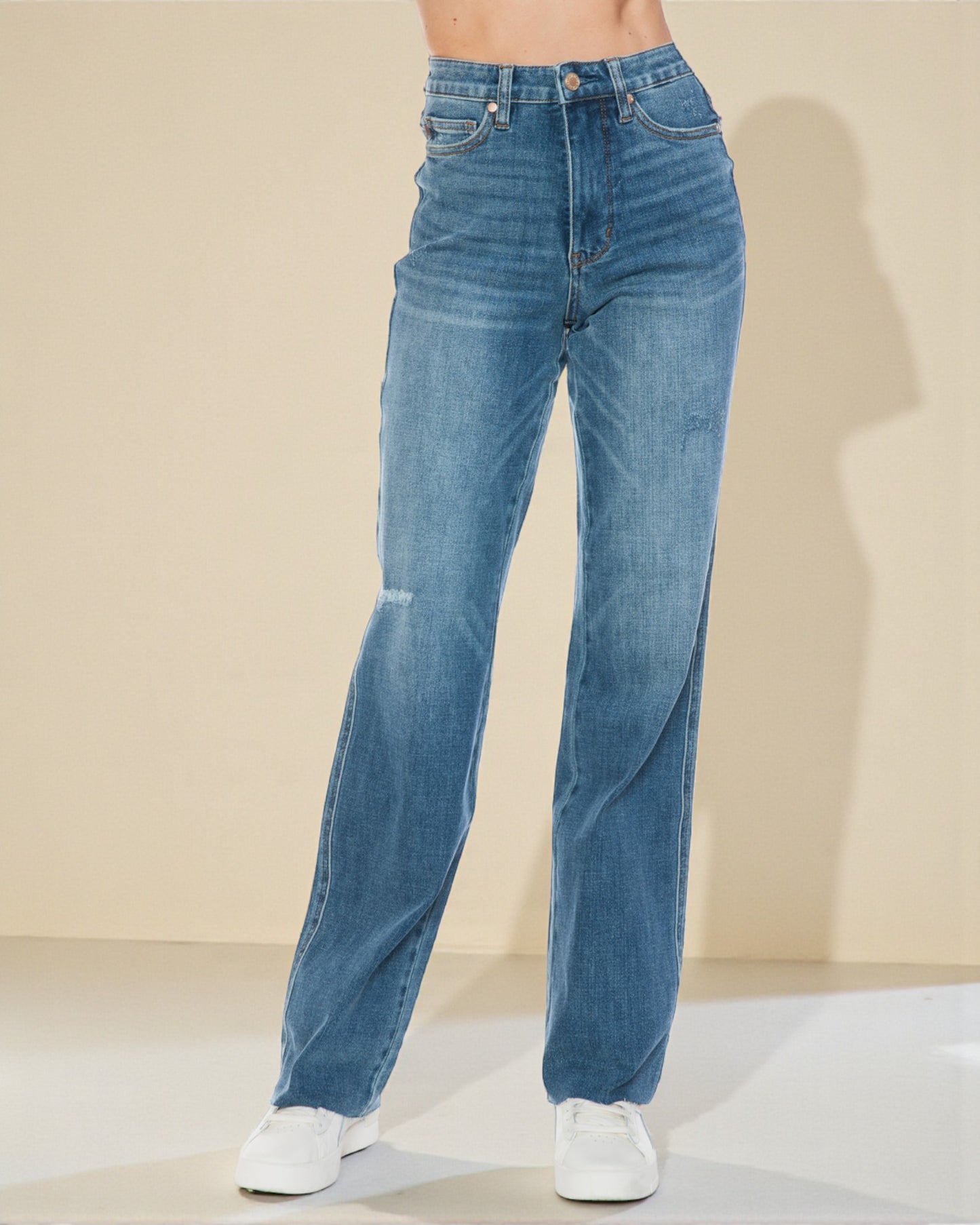 Blue jeans worn by a person on a beige background
