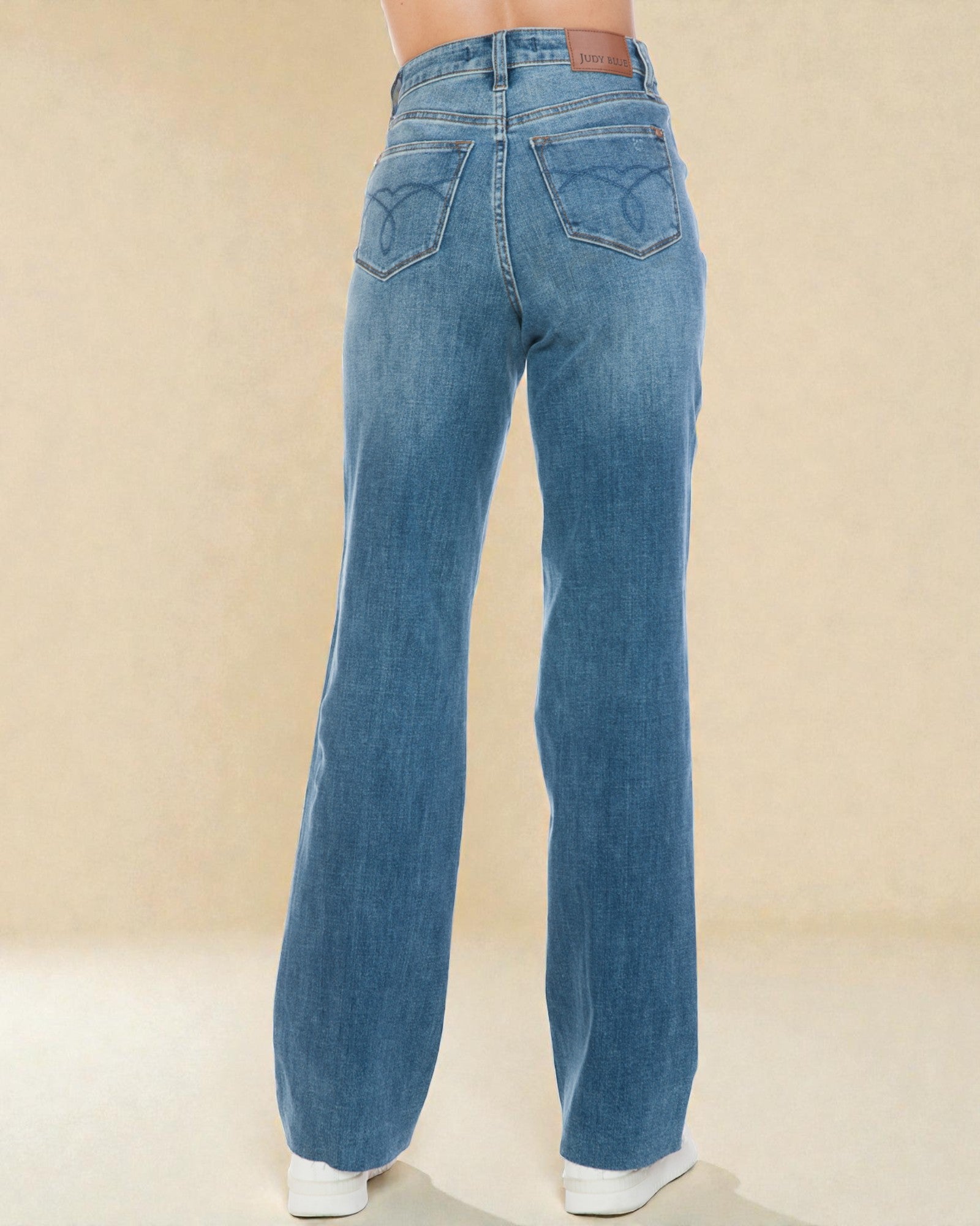 Blue jeans worn by a person on a beige background