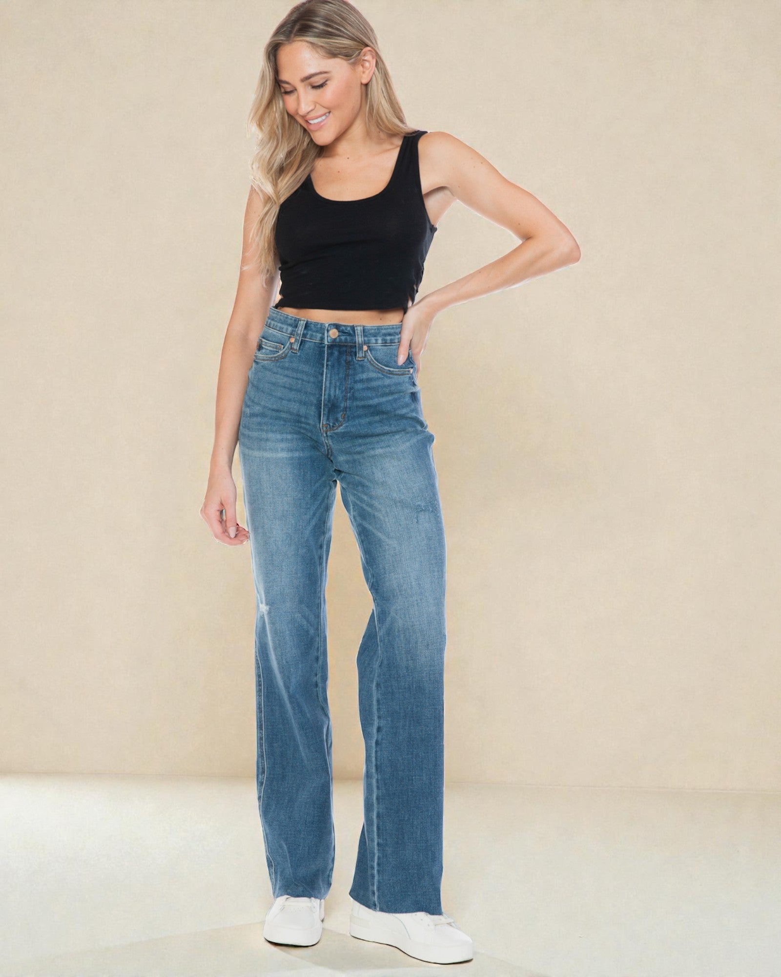 Woman wearing blue jeans and a black top on a beige background