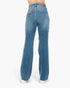 Rear view of a person wearing medium-wash blue jeans with a straight-to-wide leg fit, shown against a plain light gray studio background.