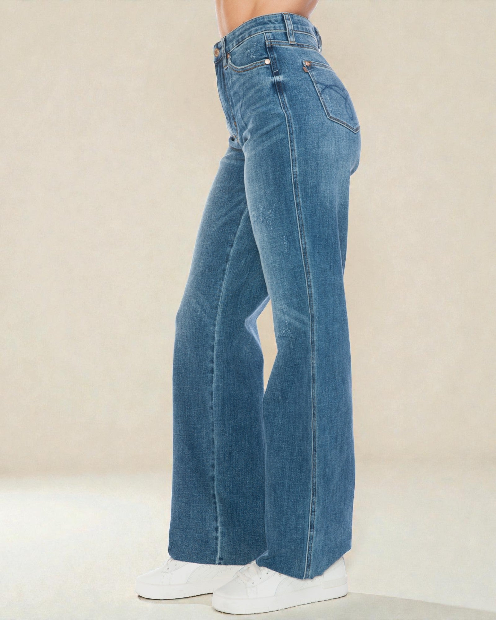 Blue jeans worn by a person on a plain background