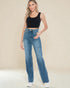 Woman wearing blue jeans and a black top against a beige background