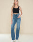 Woman wearing blue jeans and a black top against a beige background