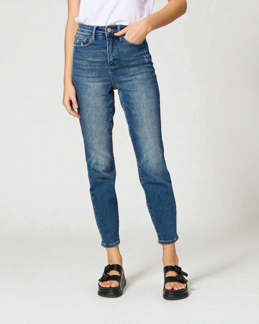 Person wearing blue jeans and black sandals on a white background