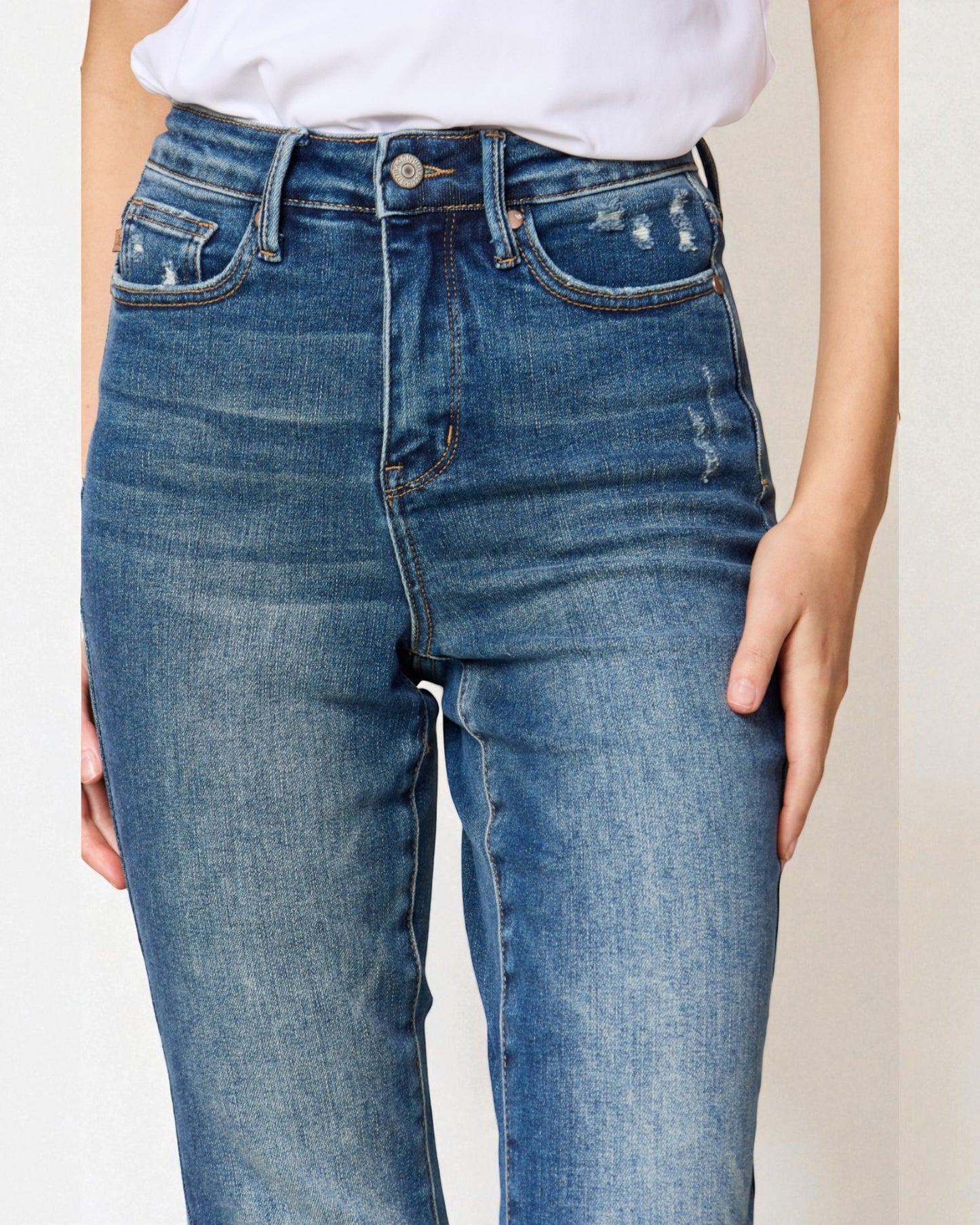 Blue jeans worn by a person on a plain background
