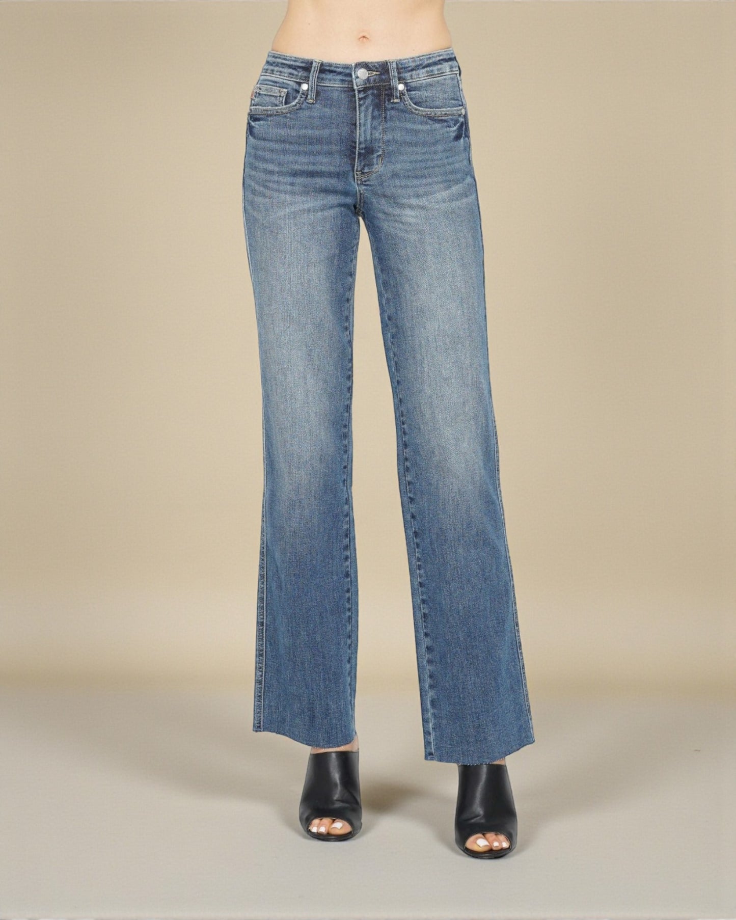 Blue jeans worn by a person on a beige background