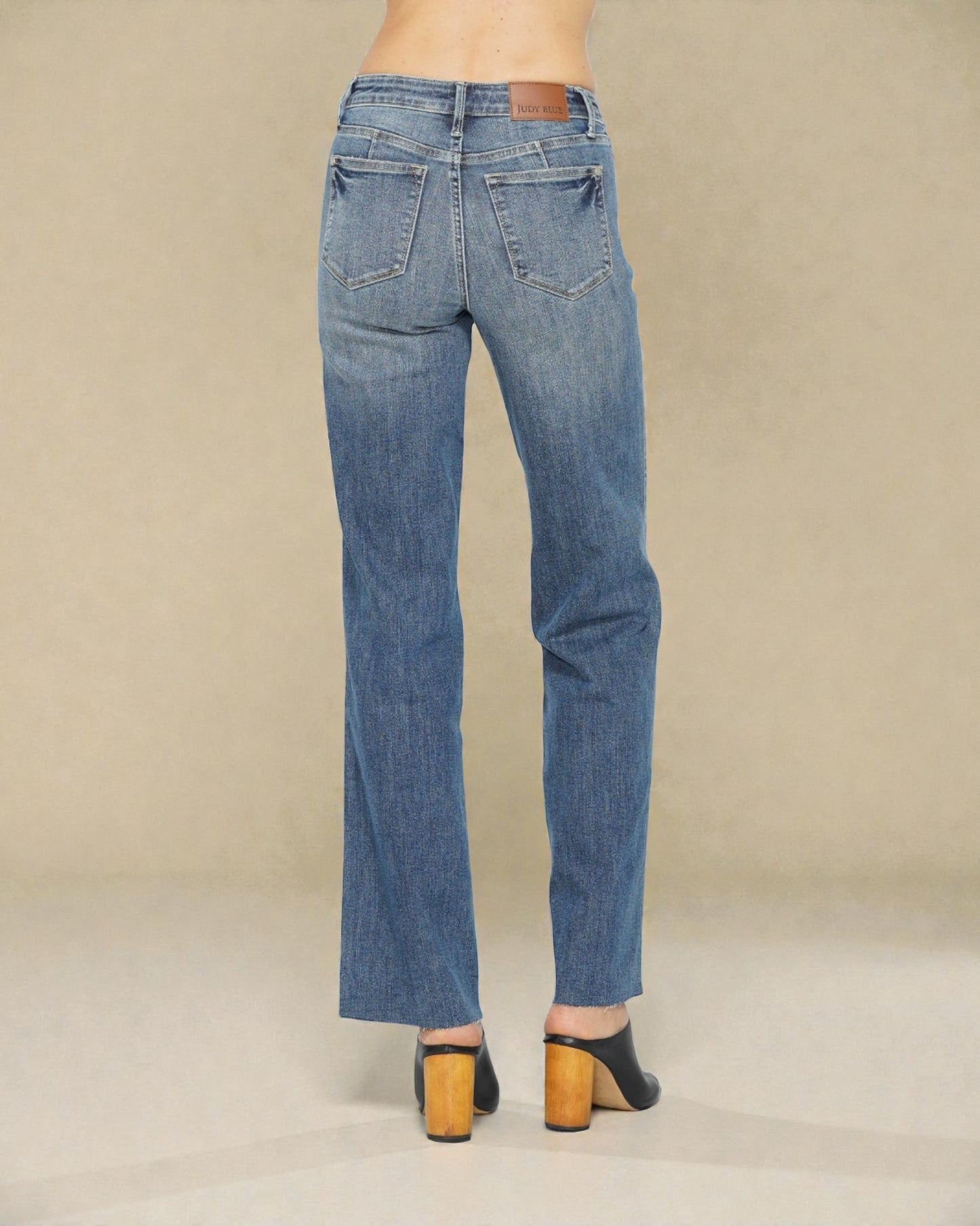 Blue jeans worn by a person on a beige background