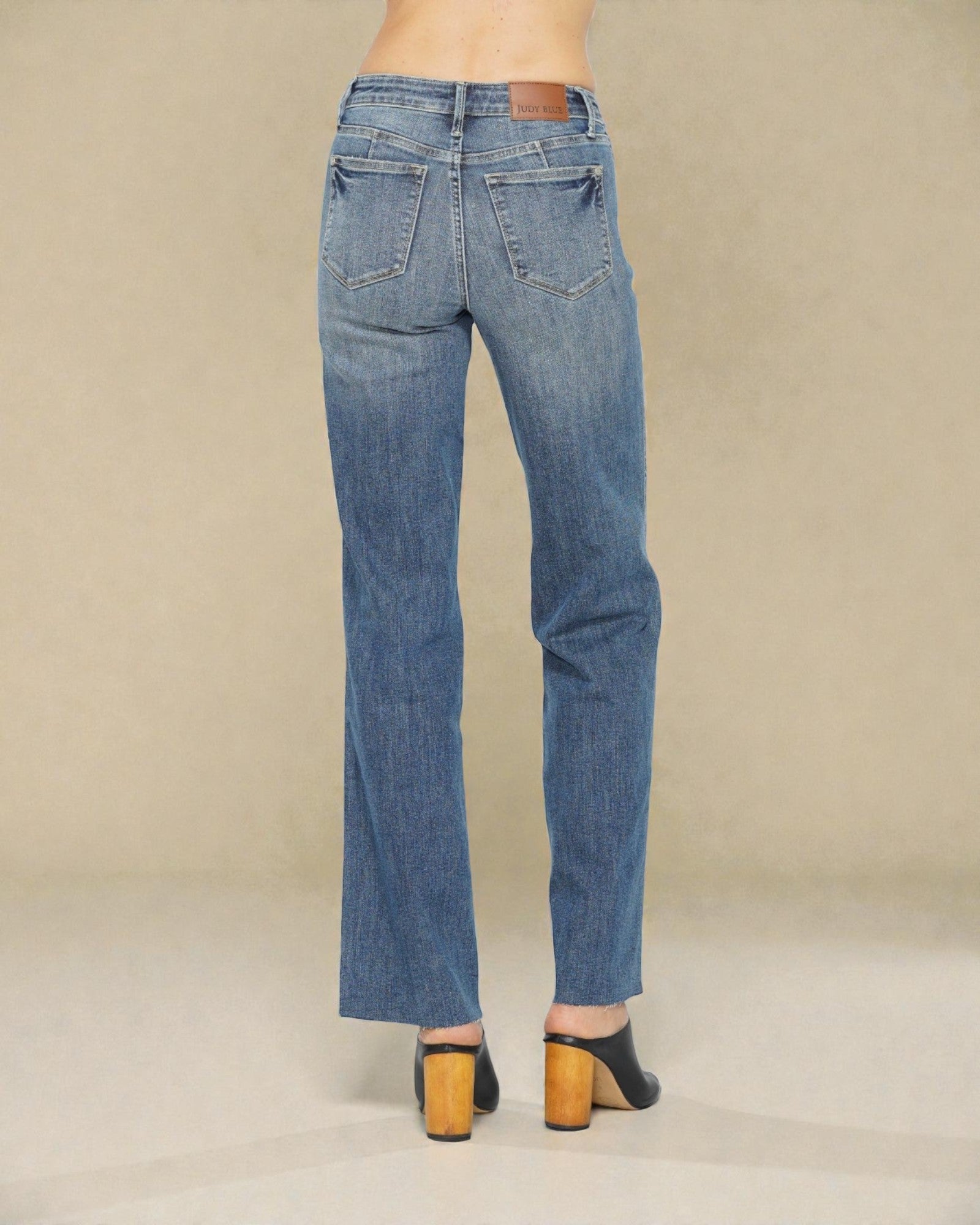 Blue jeans worn by a person on a beige background
