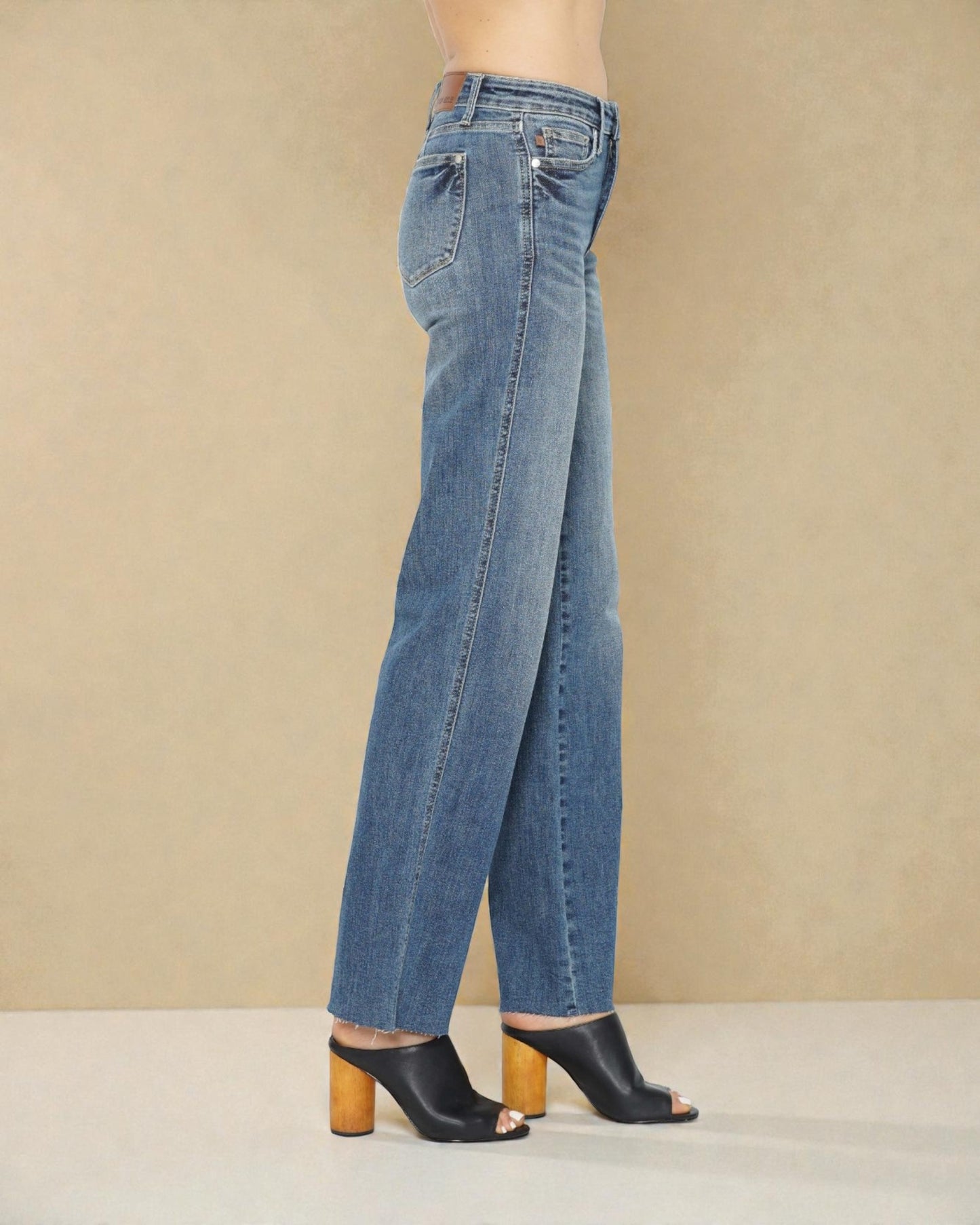 Blue jeans worn by a person on a beige background