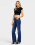 Woman wearing blue jeans and a black crop top on a white background