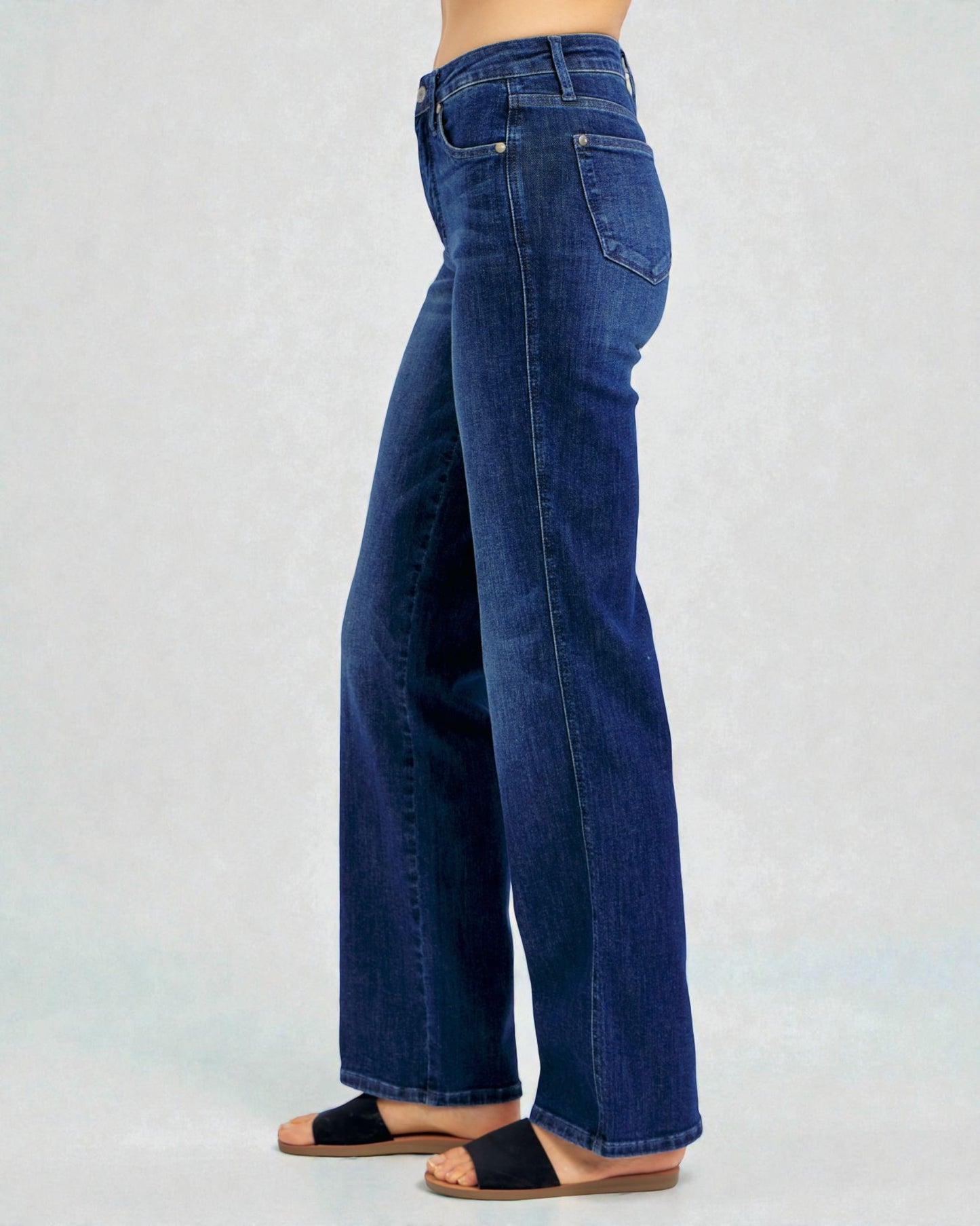 Person wearing blue jeans on a light gray background