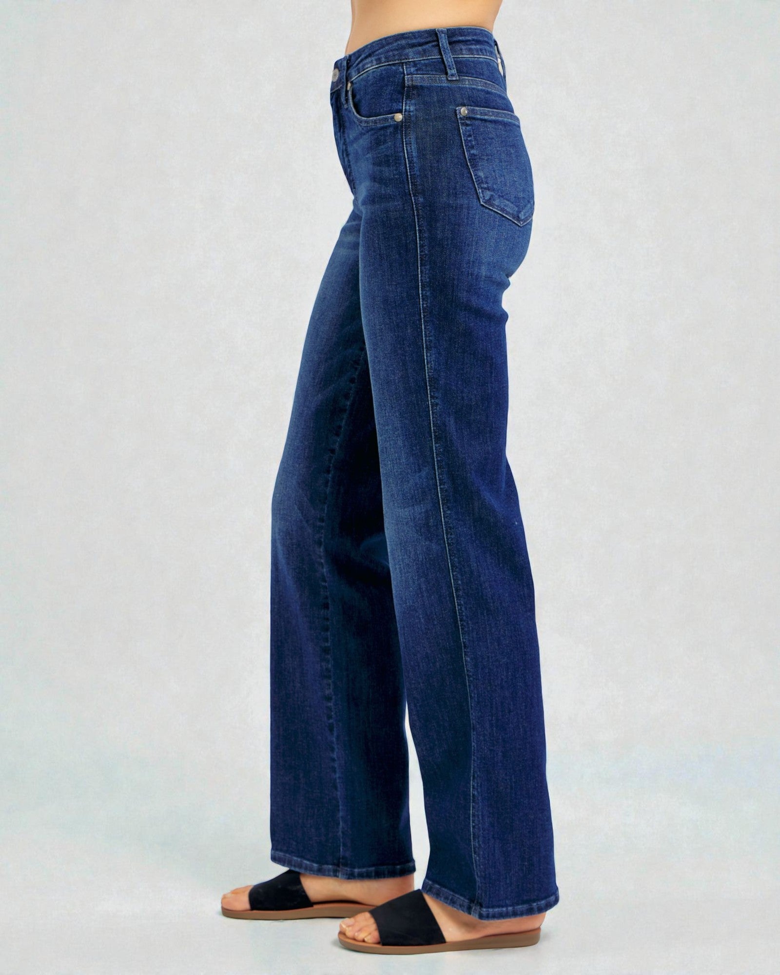 Person wearing blue jeans on a light gray background