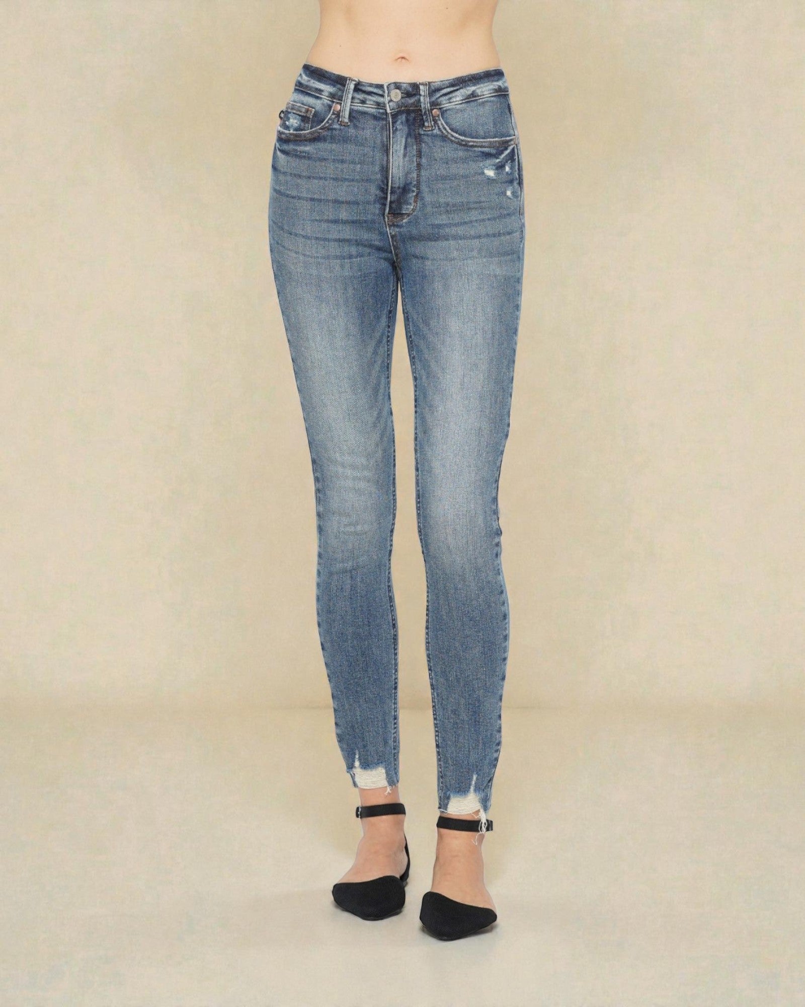 Blue jeans worn by a person on a beige background