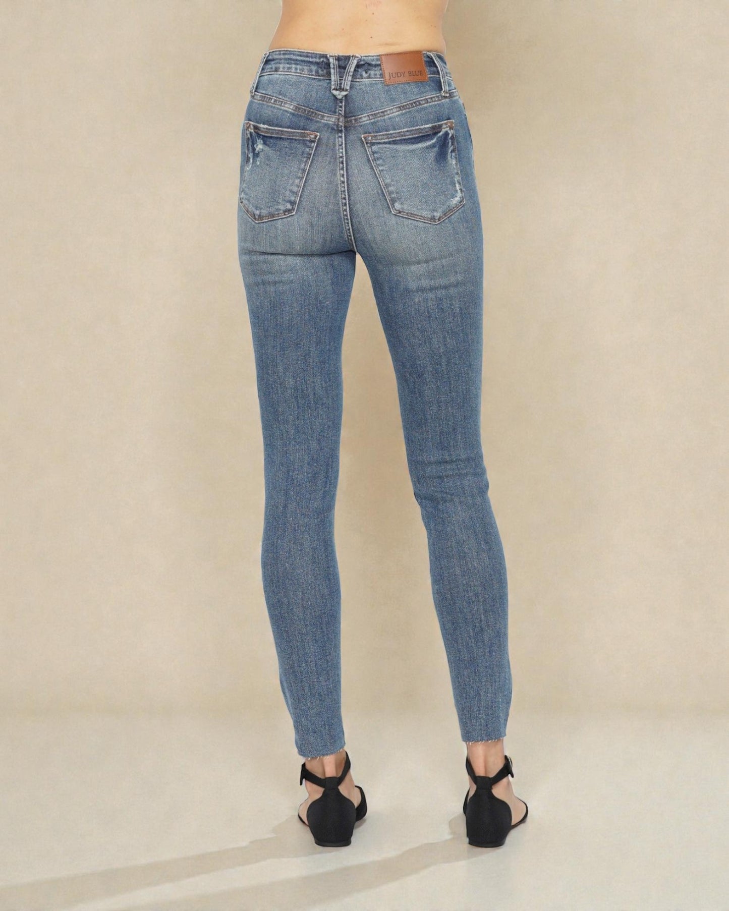 Blue jeans worn by a person on a beige background