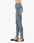 A side profile view of a model wearing light blue high-waisted skinny jeans with distressed details, paired with black flat sandals, against a plain white background.