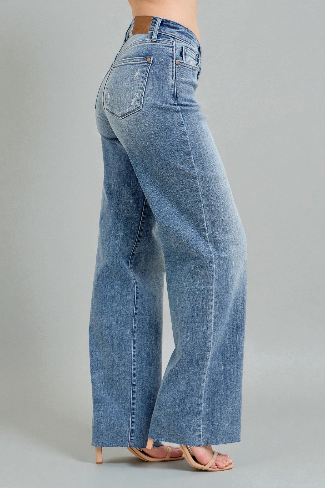 Blue jeans worn by a person on a gray background