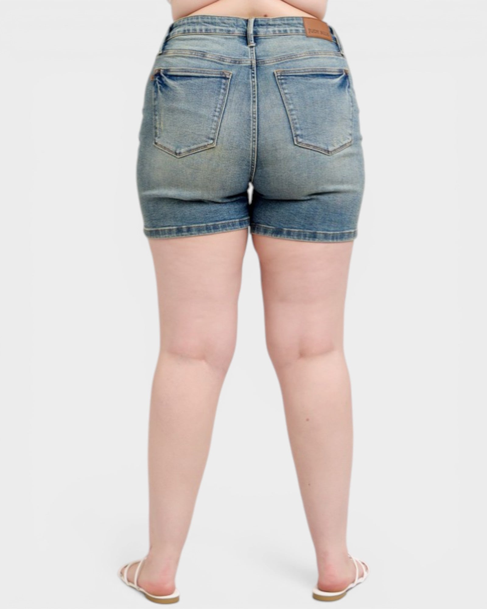 Denim shorts worn by a person on a white background