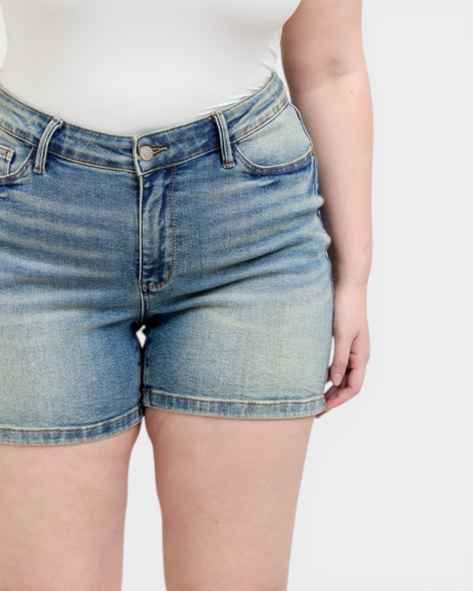 Person wearing blue denim shorts on a plain background